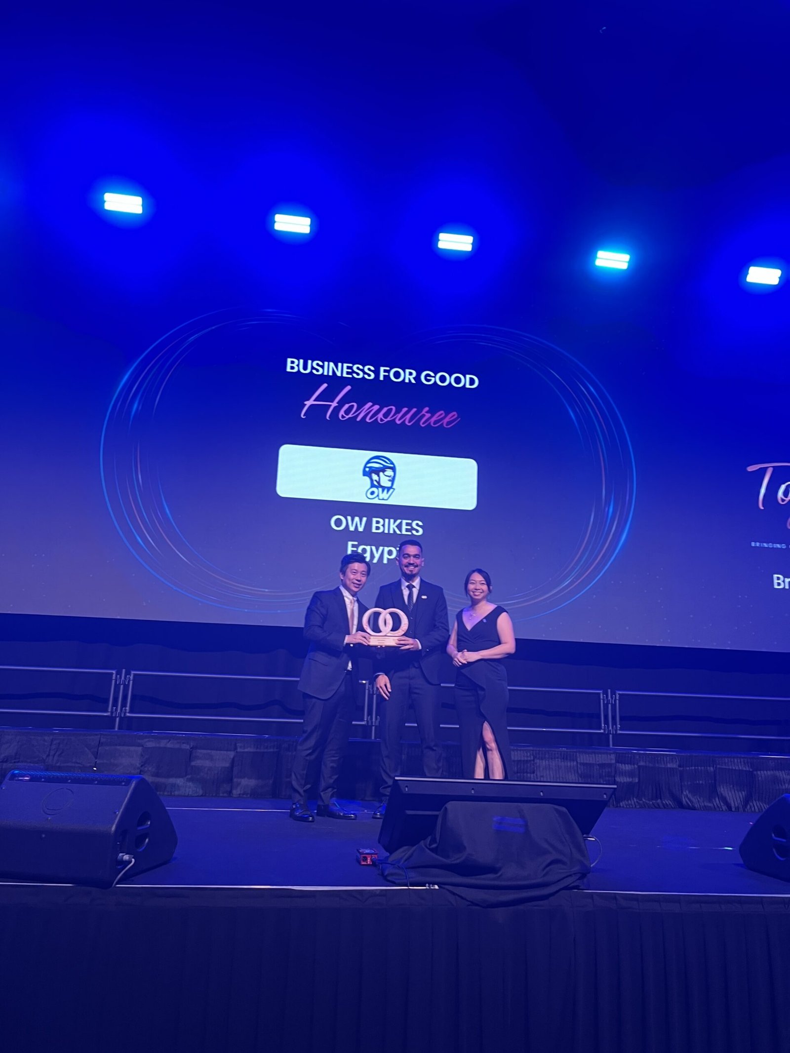 Omar Walid receiving trophy on stage with blue illumination